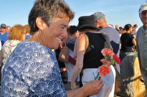 Greenlaw handed out orange and red carnations, which Gloucester fishing families ceremoniously tossed into Gloucester Harbor. (Susan Pollack photo)