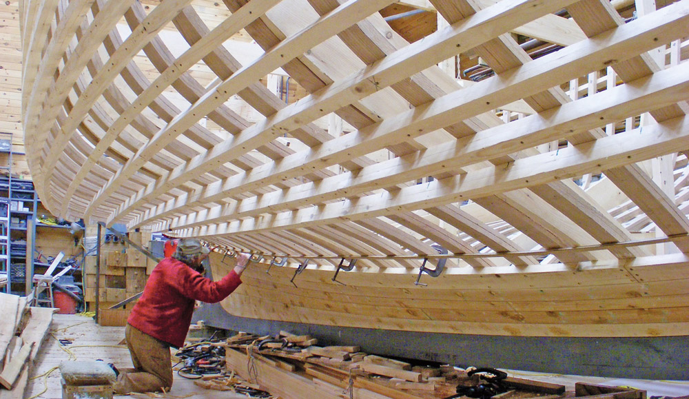 Richard Stanley at work beneath the 38-footer underway in his Bass Harbor shop.  (Brian Robbins photo)
